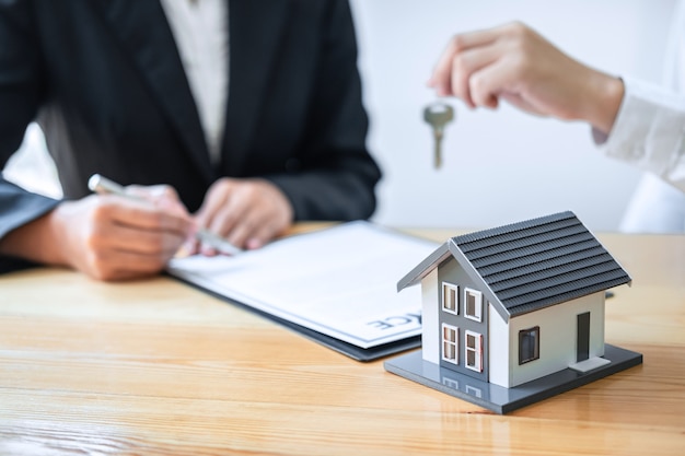 Koncepcja ubezpieczenia domu i inwestycji w nieruchomości, Agent sprzedaży dający klucz do domu nowemu klientowi po podpisaniu umowy z zatwierdzonym wnioskiem o wydanie nieruchomości.
