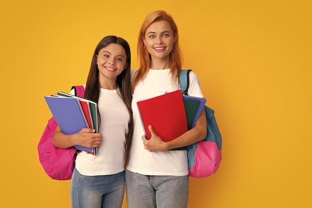 Koncepcja uczenia się i edukacji w szkole Matka i córka uczennice ze szkolnym plecakiem i książkami gotowymi do nauki Powrót do szkoły Mama i dziecko na na białym tle żółtym studio