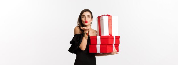Koncepcja uroczystości i świąt Bożego Narodzenia ładna kobieta w eleganckiej czarnej sukience trzymająca prezenty wyślij