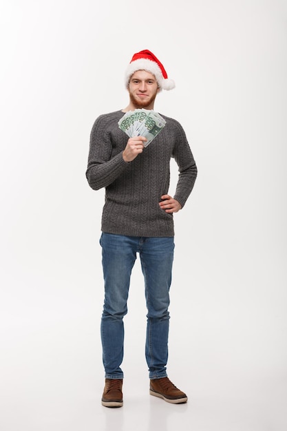 Koncepcja wakacje Młody broda mężczyzna w swetrze pokazując pieniądze do kamery