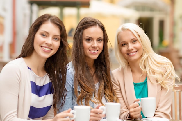 koncepcja wakacji, jedzenia i turystyki - trzy piękne dziewczyny pijące kawę w kawiarni