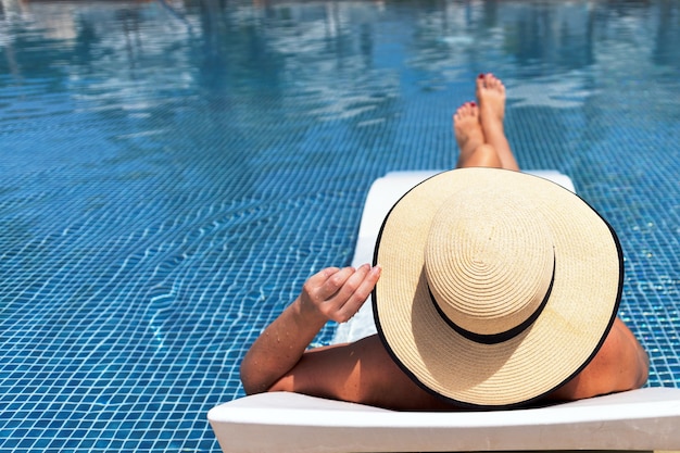 Koncepcja wakacji letnich. Kobieta w kapeluszu relaksuje się na basenie.