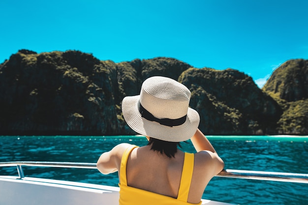 Koncepcja wakacji letnich podróży, szczęśliwy samotny podróżnik azjatycka kobieta z bikini i kapeluszem zrelaksować się w łodzi na morzu w Phuket Tajlandia
