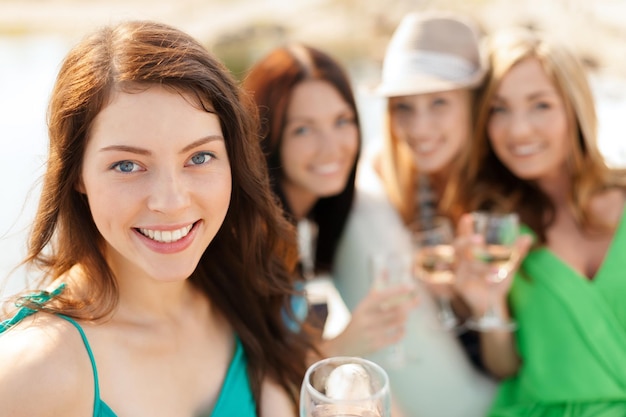 koncepcja wakacji letnich, wakacji i uroczystości - uśmiechnięte dziewczyny z kieliszkami do szampana