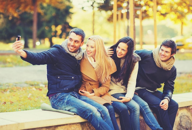 Koncepcja Wakacji, Wakacji, Podróży I Turystyki - Grupa Przyjaciół Lub Par Bawiących Się W Jesiennym Parku I Robiących Selfie
