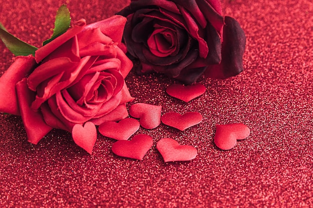 Koncepcja walentynki czerwone szkarłatne róże i wiele czerwonych serc na czerwonym tle brokatu pocztówka b...