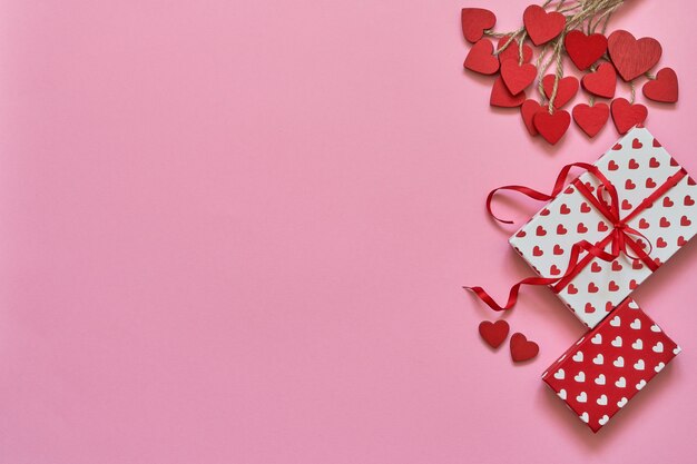 Koncepcja Walentynki. Czerwoni serca i prezentów pudełka na różowym tle.