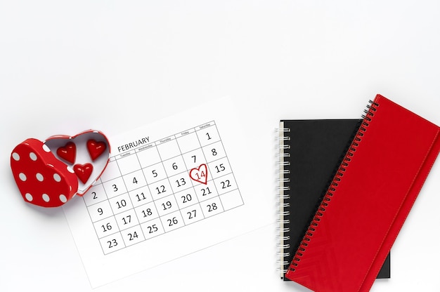Koncepcja Walentynki. Kalendarz z cukierkami w kształcie serca w czerwonym pudełku i notatniku. Widok płaski, widok z góry