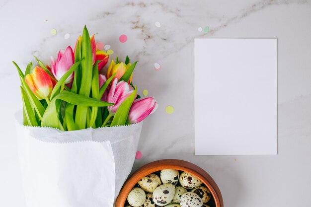 Koncepcja Wielkanoc. Różowi i czerwoni tulipany z białym czystym pustym miejscem dla twój teksta i przepiórek jajek na marmurowym tle. Skopiuj miejsce, mieszkanie świeckich.