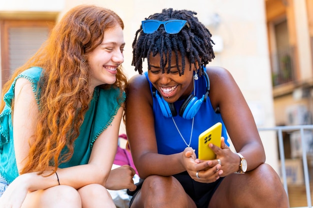 Koncepcja wieloetniczna Młode kobiety uśmiechają się i łączą podczas korzystania ze smartfona