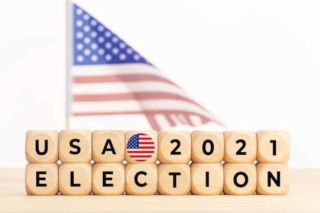 Koncepcja wyborów USA 2021. Drewniany blok z tekstem i amerykańską flagą w tle. Skopiuj miejsce