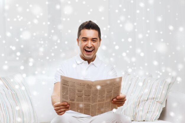 koncepcja wypoczynku, informacji, ludzi i środków masowego przekazu - szczęśliwy człowiek czytający gazetę i śmiejący się w domu z efektem śniegu