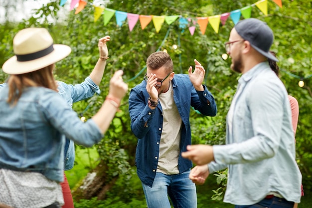 koncepcja wypoczynku, wakacji, zabawy i ludzi - szczęśliwi przyjaciele tańczący na letniej imprezie w ogrodzie