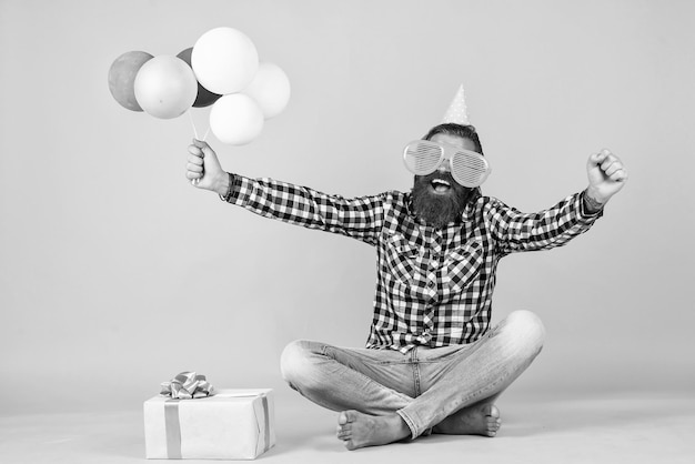 Koncepcja zabawy i szczęścia szczęśliwy człowiek trzyma kolorowe balony z helem hipster uśmiecha się radośnie bawi się na imprezie przygotowuje się do wakacji Menedżer wydarzeń pozuje ze świątecznym dodatkiem