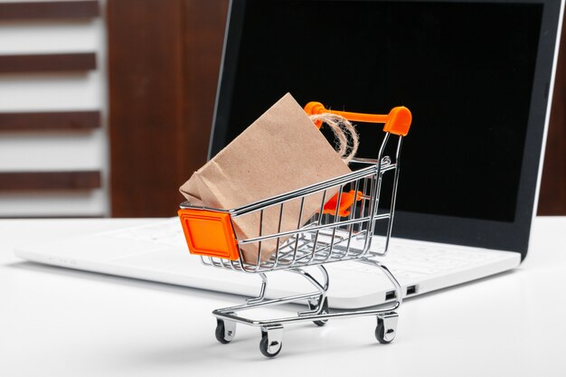 Zdjęcie koncepcja zakupów online, koszyk, laptop na biurku