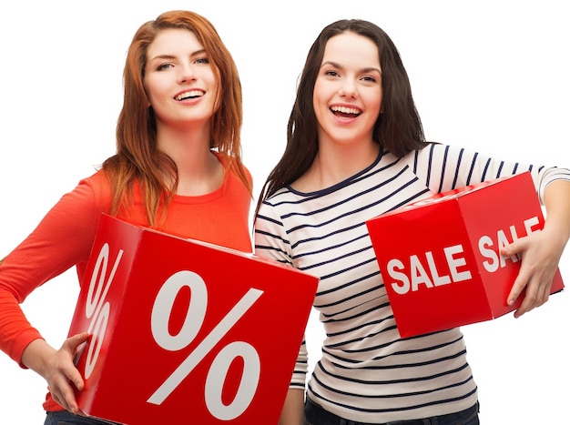 koncepcja zakupów, sprzedaży i prezentu - dwie uśmiechnięte nastolatki z procentem i znakiem sprzedaży na czerwonym pudełku