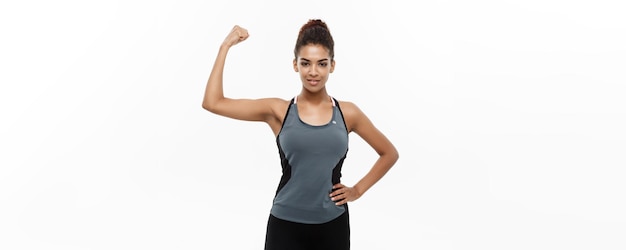 Koncepcja zdrowego i fitness portret młodej pięknej afroamerykanki pokazującej jej silne mięśnie