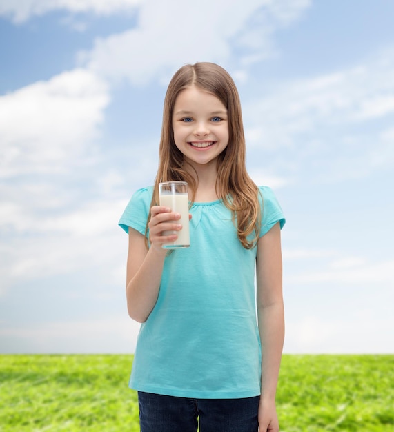 koncepcja zdrowia i urody - uśmiechnięta dziewczynka ze szklanką mleka