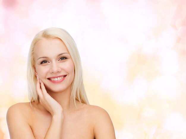 koncepcja zdrowia i urody - uśmiechnięta młoda kobieta dotyka skóry twarzy