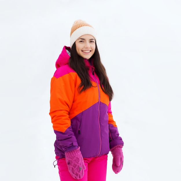 koncepcja zimy, wypoczynku, odzieży i ludzi - szczęśliwa młoda kobieta lub nastolatka w zimowych ubraniach na zewnątrz