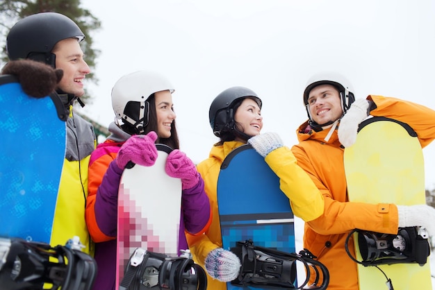 Zdjęcie koncepcja zimy, wypoczynku, sportów ekstremalnych, przyjaźni i ludzi - szczęśliwi przyjaciele w kaskach z rozmowami na snowboardach