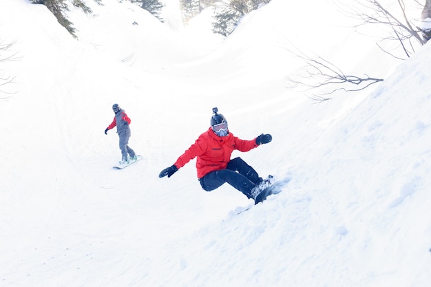 Koncepcja zimy, wypoczynku, sportu i ludzi - aktywny snowboardzista skaczący w górach w słoneczny dzień. Snowboard zbliżenie. Ośrodek narciarski Sheregesh