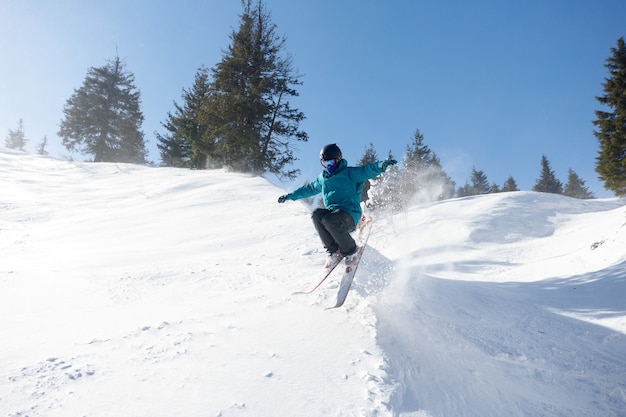 Koncepcja zimy, wypoczynku, sportu i ludzi - narciarz w górach, przygotowany stok i słoneczny dzień. Szczęśliwy narciarz. Sport ekstremalny.