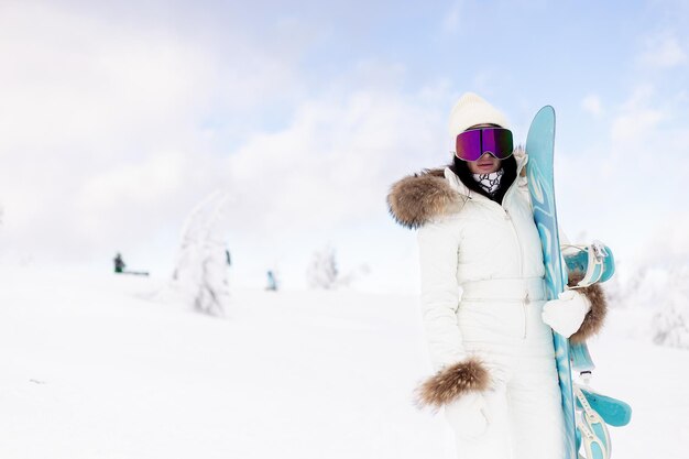 Koncepcja zimy, wypoczynku, sportu i ludzi - snowboardzistka sportowa na śniegu nad błękitnym niebem