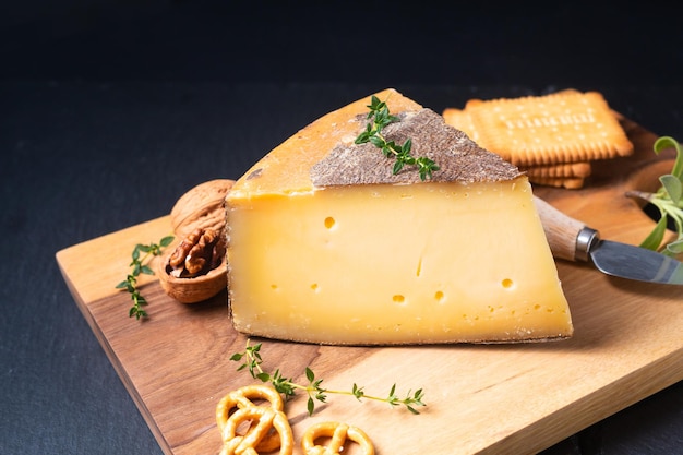Zdjęcie koncepcja żywności francuski ser tomme de savoie na desce na czarnym tle z miejscem na kopię