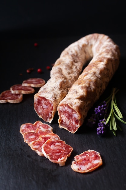 Koncepcja żywności organiczne francuskie salami Saucisson na czarnej tablicy łupkowej z miejscem na kopię