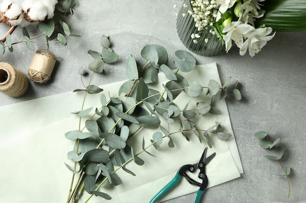 Koncept florystyczny z eukaliptusem, kwiatami i bawełną na szarym stole