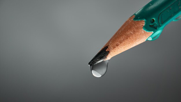 Końcówka ołówka z kroplą na szarym tle