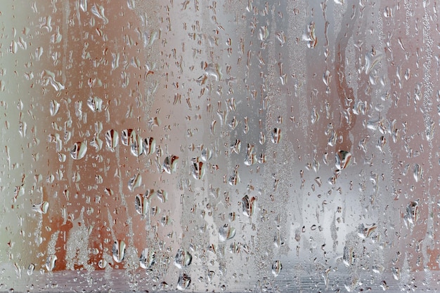 Kondensacja na przezroczystym oknie, krople wody, deszcz. Szyba okienna o dużej wilgotności powietrza. Tło naturalnej kondensacji wody