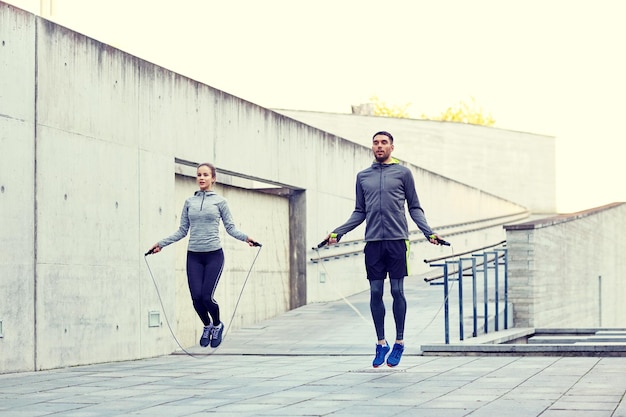 kondycja fizyczna, sport, ludzie, ćwiczenia i styl życia - mężczyzna i kobieta skaczący na linie skoku na świeżym powietrzu