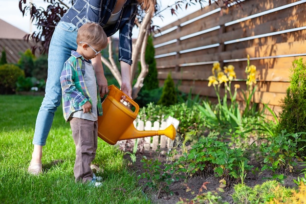 Konewka dla dziecka i matki podlewa ogródek na podwórku