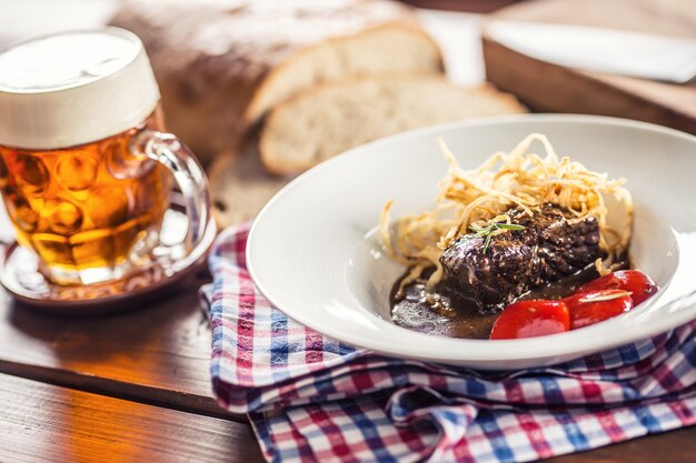 Konfitowany stek wołowy z sosem smażonym cebulowym chlebem beczkowym i dekoracją w pubie lub restauracji.