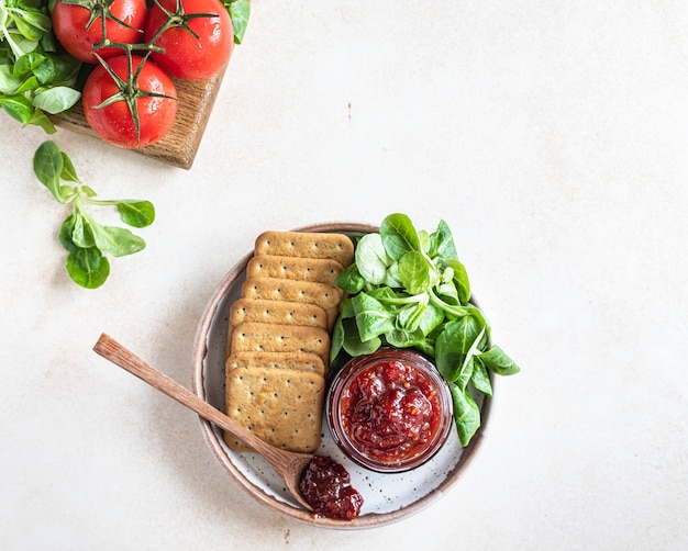 konfitura lub sos pomidorowy w słoiku z krakersami i sałatką z zielonych liści niezwykły dżem pikantny
