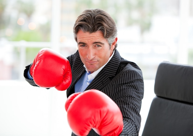 Konkurencyjny biznesmen jest ubranym bokserskie rękawiczki