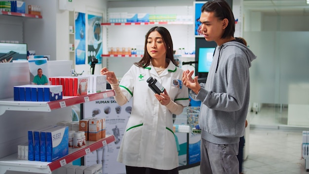 Konsultant medyczny pokazujący klientowi butelkę pigułek, dający leki na receptę i środki ochrony zdrowia z półek. Specjalista rozmawia z klientem o produktach farmaceutycznych.