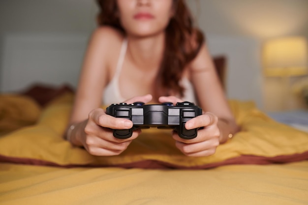 Kontroler w rękach młodej kobiety grającej w gry wideo w domu
