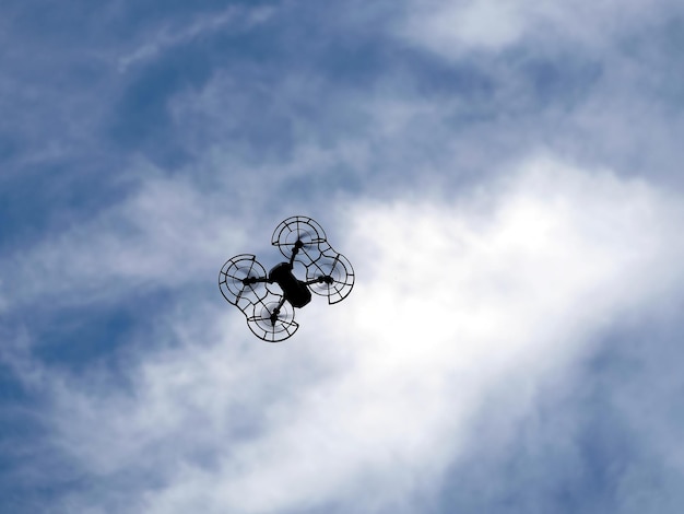 Zdjęcie kontur quadrocoptera z siatką ochronną silnika latającą na niebieskim niebie od dołu do góry