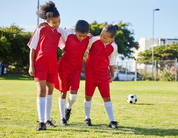Kontuzja piłki nożnej i zespół dzieci pomagają wspierać i chodzić z rannym przyjacielem podczas gry na boisku sportowym Wypadek sportowy i dziecięca grupa piłkarska pomagająca zawodniczce po treningu fitness i meczu