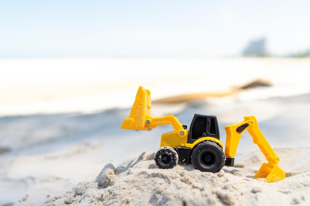 Zdjęcie koparko-zabawka żółty plastik na piasku na plaży