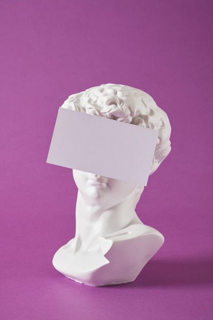 Kopia głowy antycznego posągu Dawida z białym pustym pustym talerzem na fioletowym tle