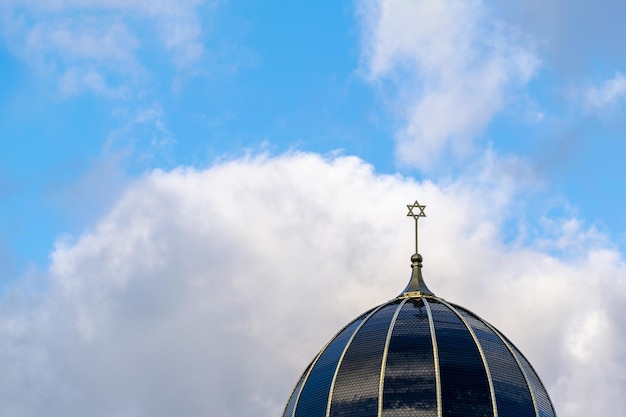 Kopuła budynku synagogi pokryta jest ciemnymi dachówkami i podzielona na sektory z pochmurnym niebem w tle