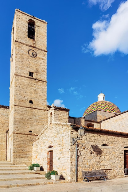 Kopuła kościoła Chiesa di San Paolo Apostolo i dzwonnica w starym mieście Olbia na wyspie Sardynia we Włoszech. Katedra i dzwonnica na wyspie Sardynii. Błękitne niebo z białymi chmurami na tle.