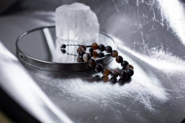 Koraliki z wielobarwnych kamieni naturalnych leżą na śnieżnobiałym kamieniu, topazie i kwarcu, na srebrnym tle