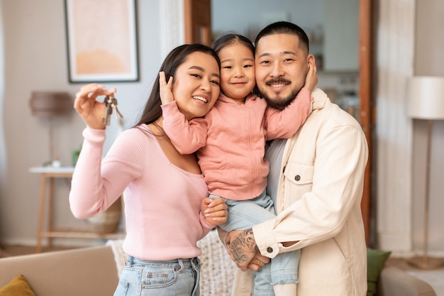 Koreańscy rodzice i córeczka pokazujący nowe klucze do domu w pomieszczeniu