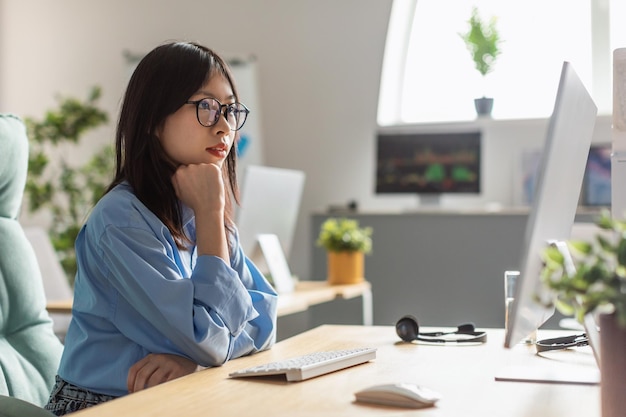 Koreańska kobieta pracująca online na komputerze przeglądającym Internet w biurze