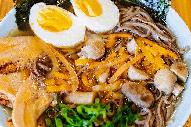 Koreański makaron Ramyeon lub Ramyun o pikantnym smaku zwieńczone żółtkiem chili pieczarkami żółtko jaj kimchi Prezentacja w koreańskim stylu